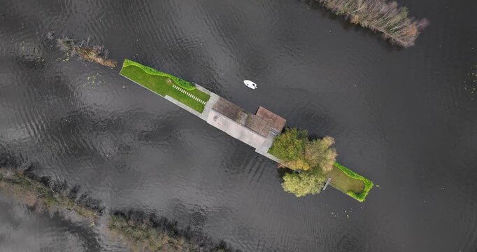 Aerial view of small boat passing by a small island with a house on Loosdrechtse Plassen lake