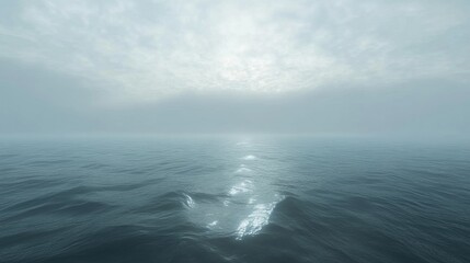 A serene sea gently mirrors the soft light that glows beneath a blanket of clouds stretching across the horizon in the peaceful early morning hours