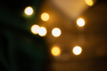 bright warm yellow lights on dark green and wooden  background,  blurred garland for holidays like Christmas and New Year