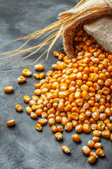 Golden corn kernels spilling from burlap sack on textured surface