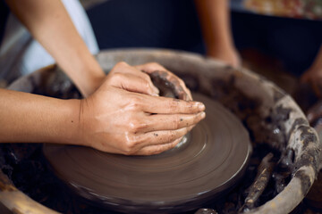 Hands of craftsman artist working on pottery wheel.