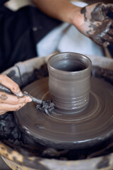 Hands of craftsman artist working on pottery wheel.