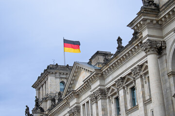 Obraz premium Waving German flag on the Reichstag building in Berlin, on a cloudy day