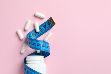 Jar of weight loss pills and measuring tape on gray background, flat lay. Space for text