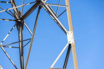 Metal structure of electrical tower connecting steel beams against blue sky