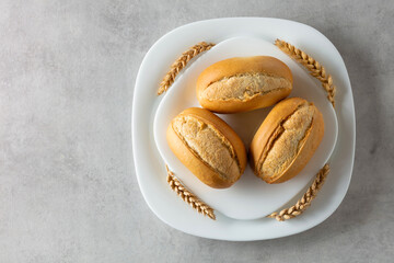 French buns and wheat ears on a marmoreal table.