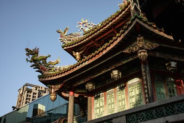 Traditional Chinese temple roof with ornate dragon carvings under a clear blue sky.