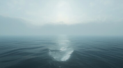 Vast ocean under a hazy sky with soft sunlight illuminating the water surface during early morning hours near the horizon