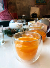 Hot sea buckthorn tea in a glass in a cafe. Vertical orientation.