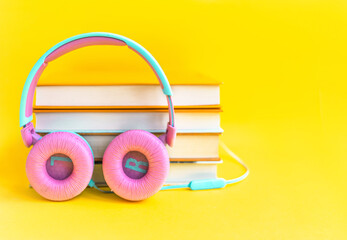Stack of books and headphones on a yellow background. Audiobook concept. Listen to lessons.
