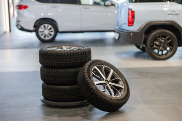 New wheels with studded tires against the background of new cars. 