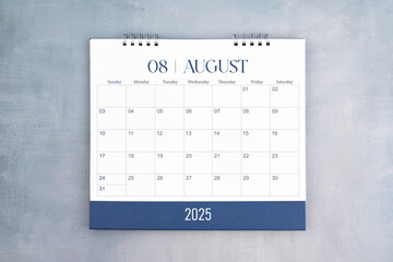 August 2025 desk calendar on gray cement wall background. Page of annual monthly calendar for plan.