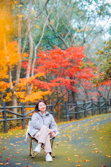 Obraz premium One Asian woman enjoying beautiful autumn foliage scenery of vibrant maple trees during December at Dujuan Valley in Xikou, Fenghua, Ningbo, Zhejiang, China