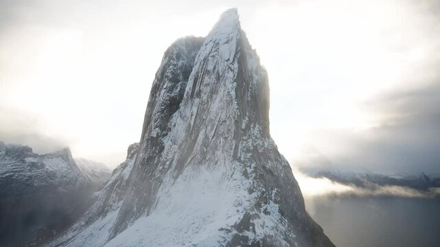 Handheld shot of a person walking up to the base of Segla mountain on the island of Senja in the Arctic Circle of Northern Norway.  A snow=capped mountain peak in the fall.