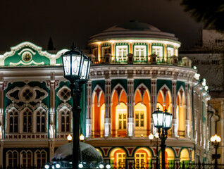 Burning lanterns on poles in the night city.