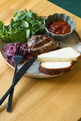 Plate with fried pork meat with sauce, bread, pickled onion and greens