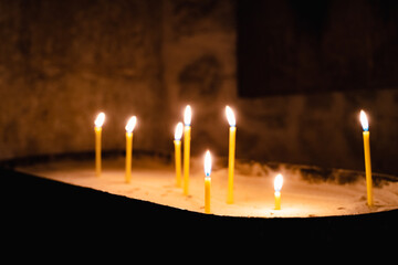 Burning candles in the ancient orthodox church. Flame of yellow candles in the old monastery....