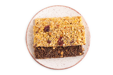 Granola bars with caramel, nuts, flakes in ceramic plate isolated on white. Top view, close up.