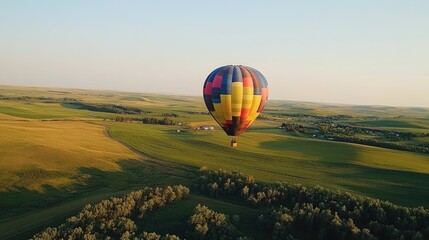 Obraz premium Hot Air Balloon Soaring Over Rolling Green Fields