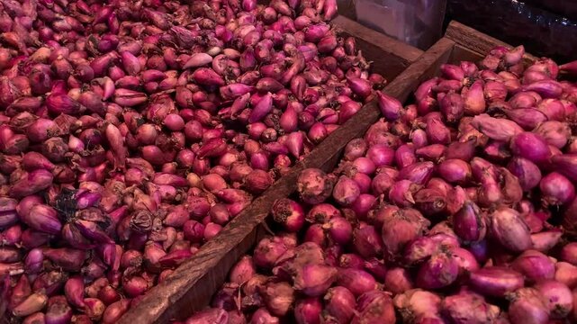 Fresh red shallots stacked for sale at a local market.
