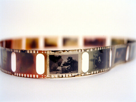 Close-up of vintage film strips with visible frames and a blurred background, evoking nostalgic cinematic aesthetics and themes of analog photography