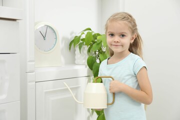 Little helper. Cute girl with watering can at home