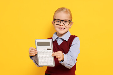 Little girl with calculator pretending to be accountant on orange background. Dreaming of future profession