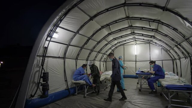 Medical staff assist patients in temporary hospital shelter during emergency response situation
