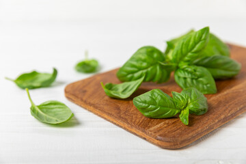 Green basil leaves on a textured wooden background. Kitchen herbs, spices. Fresh green organic basil. Vegan. Greens for salad. Place for text. Copy space.