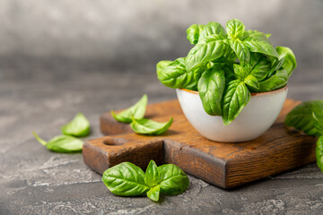 Green basil leaves on a textured wooden background. Kitchen herbs, spices. Fresh green organic basil. Vegan. Greens for salad. Place for text. Copy space.