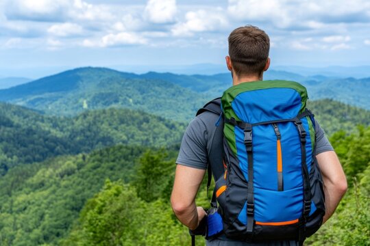 A guy hiking up a mountain trail, wearing a backpack and outdoor gear, with a scenic view behind him
