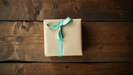 Fototapeta premium A simple gift box tied with a pale blue ribbon rests on a rustic wooden surface.