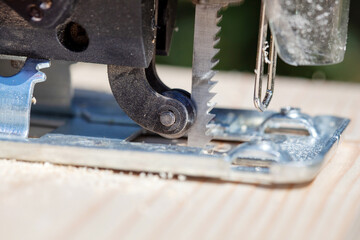 The builder works with a jigsaw. The craftsman cuts the board with a jigsaw.