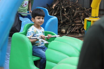 4 year old Indian boy is enjoying aero plane ride in a amusement park in Pune India. He is trilled...