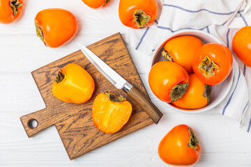 Persimmon on textured wooden background. Persimmon fruit. A piece of ripe, juicy, sweet persimmon fruit. Vegan. Orchard. Close-up. Space for text. Copy space.