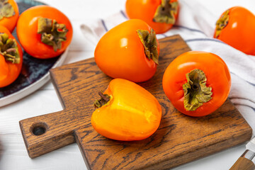 Persimmon on textured wooden background. Persimmon fruit. A piece of ripe, juicy, sweet persimmon fruit. Vegan. Orchard. Close-up. Space for text. Copy space.