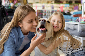 Portrait of cheerful smiling mother and daughter cuddling with dog