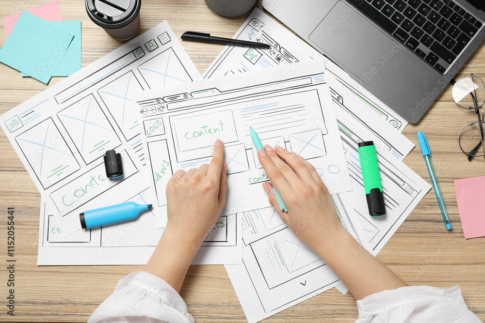 Poster website designer creating wireframe on paper with pen at wooden table, top view