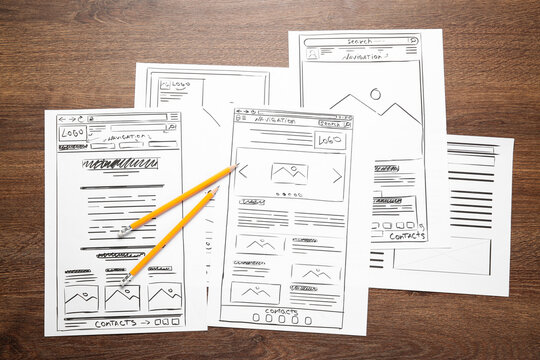 Developing UI design. Sketches of website wireframes and pencils on wooden table, top view