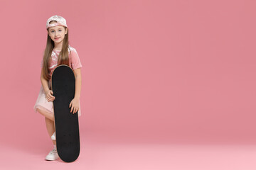 Little girl with skateboard against pink background, space for text