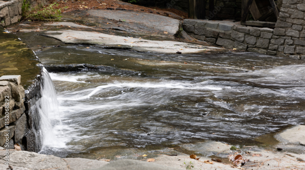 Wall mural Water cascading around rocks