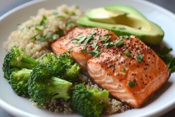 Healthy salmon dish with quinoa, broccoli, and avocado garnished with herbs served on a white plate