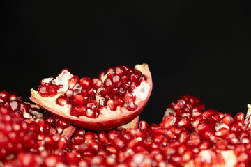 Pomegranate background, lots of peeled pomegranates and seeds, black background