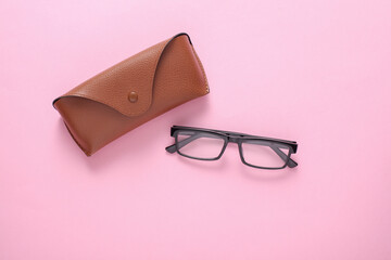 Leather case with eyeglasses on pink background