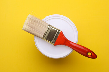 Clean paintbrush with paint can on yellow background. Top view