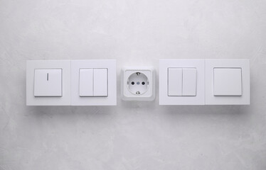 Light switches and electrical socket on grey concrete background