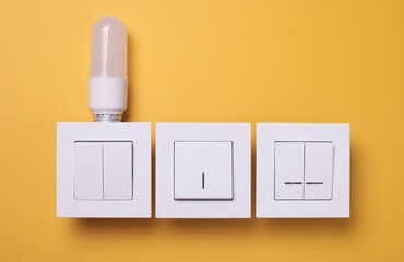 Light switches with light bulb on yellow background