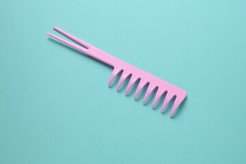 Pink plastic comb on mint green background.