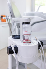Vertical close-up of an Air Flow dental cleaning device with powder and water containers, used for...