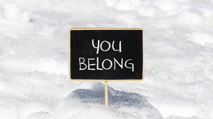 Belonging and you belong symbol. Concept words You belong on beautiful yellow chalk blackboard. Beautiful white snow background. Business belonging and you belong concept. Copy space.